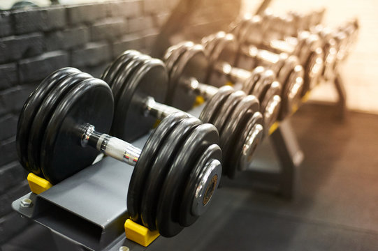 dumbbells row in a gym. sport sunny background