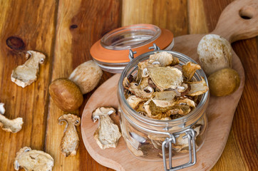 Dried forest mushrooms in a glass jar on a wooden background
