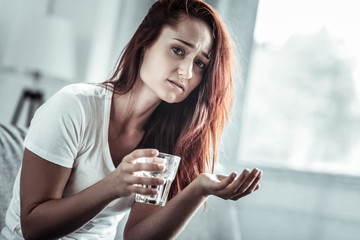 Just take it. Attractive girl wrinkling forehead while suffering pain, going to take medicine