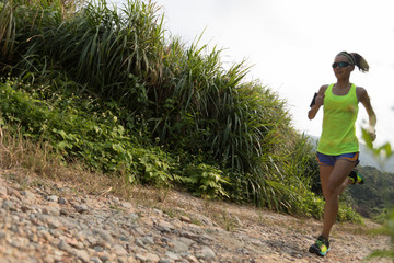 young fitness woman trail runner running on rocky mountain trail