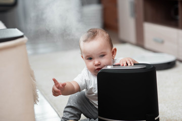 Little baby looks at the humidifier. Moisture in the house concept