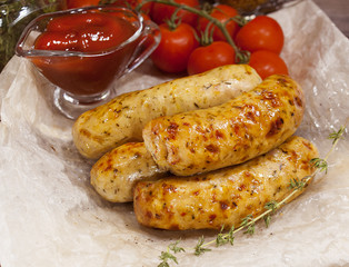 Fried pork sausages with spices and ketchup on crumpled wrapping paper.  Delicious food for gourmets, lovers of sausages and beer.