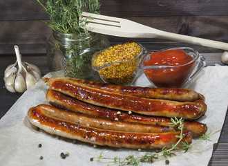Fried long Bavarian sausages, mustard and ketchup on a wooden table. Delicious food for gourmets, lovers of sausages and beer.