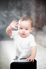 Fototapeta premium Little baby looks at the humidifier. Moisture in the house concept