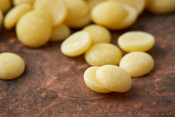 Organic cacao butter buttons (wafers) on rustic background