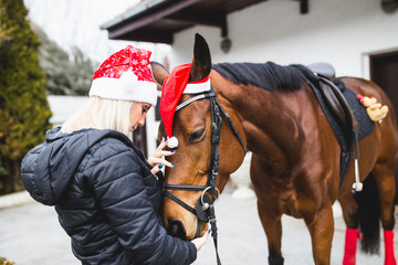 Beautiful young woman enjoying with her horse in winter holidays.