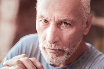 Shrewd glance. Close up of elderly man being serious while looking at you and expressing calmness