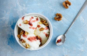 Vanilla ice cream with walnuts and fruit syrup in a blue bowl.