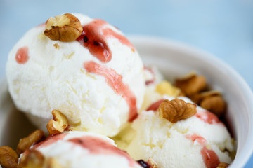 Vanilla ice cream with walnuts and fruit syrup in a blue bowl.