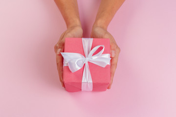 Woman holding gift box on color background