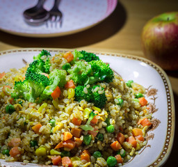 A healthy fried rice mixed with vegetables like carrots, green peas and topped with broccoli, 