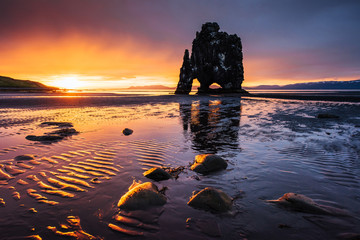 Hvitserkur is a spectacular rock in the sea on the Northern coast of Iceland. Legends say it is a petrified troll. On this photo Hvitserkur reflects in the sea water after the midnight sunset - obrazy, fototapety, plakaty