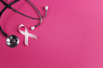 Pink ribbon and stethoscope on pink background with copy space. Breast cancer awareness symbol.