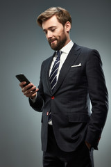 A man in a business suit with a smartphone.