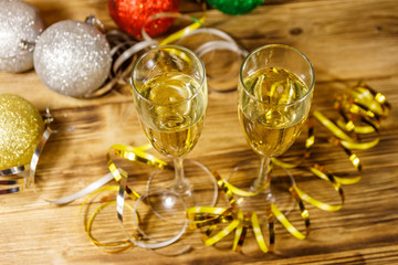Two glasses of champagne and festive Christmas decorations on wooden table. Christmas and New Year celebration