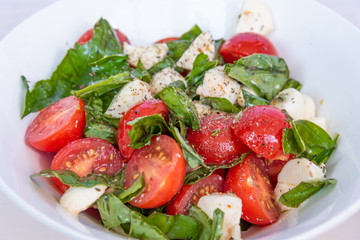 Delicious salad Caprese from cherry tomatoes and mozzarella with basil close up