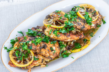 Chicken francese - fried chicken breast with lemon slices and delicious sauce on a white plate...