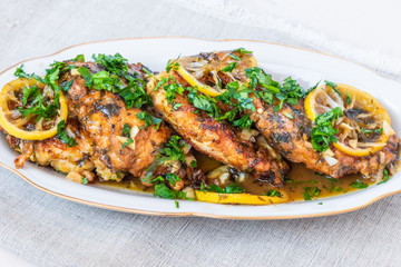 Chicken francese - fried chicken breast with lemon slices and delicious sauce on a white plate close-up, top view