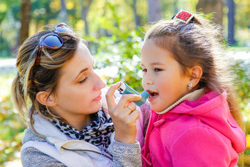 caring mom helps girl to use an inhaler against asthma - obrazy, fototapety, plakaty