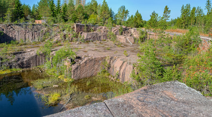 Fototapeta na wymiar Blue pond formed at the bottom of the abandoned granite quarry.