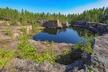 Obraz premium Blue pond formed at the bottom of the abandoned granite quarry.