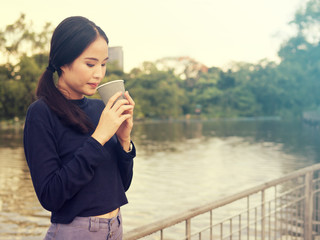 Beautiful women have enjoyed in the garden with coffee.Asian women drinking coffee.Asian girls like to drink coffee. Beautiful Asian girl inhale the smell of coffee.