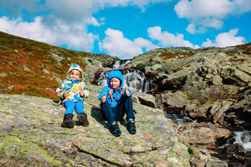 little boy and girl enjoy travel in nature at waterfall