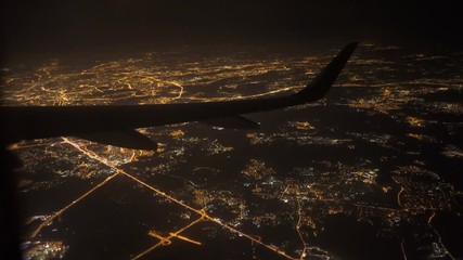 View from airplane with wing. flying at night over city light and street - Powered by Adobe