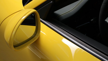 Specchietto di una automobile tedesca dalla carrozzeria giallo brillante - obrazy, fototapety, plakaty