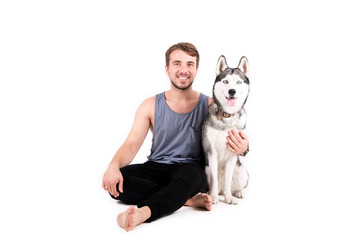 Young bearded man hanging out out with his husky dog. Hipster male wearing plain blank grey tank top spending quality time with four legged pet friend. Close up, copy space, background © Evrymmnt