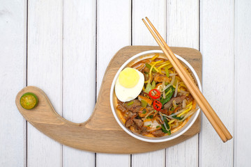 Mee Rebus in the bowl  with chopsticks on white table This dish is made of noodles ,vegetable,egg...
