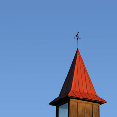 Steeple with Weather Vain Against a Blue Sky
