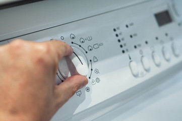 closeup of hands on washing machine dashboard