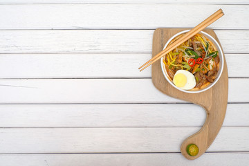 Mee Rebus in the bowl  with chopsticks on white table This dish is made of noodles ,vegetable,egg...