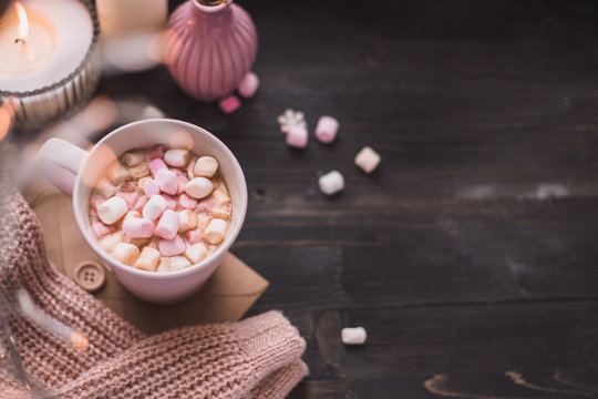 Fototapeta Mug of hot cocoa or hot chocolate with marshmallow and lights bokeh on wooden background