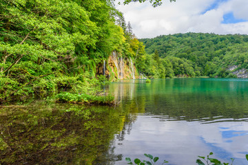 PLITVICE NATIONAL PARK, CROATIA - JUNE 8, 2018: Tourist group by the lake in the Plitvice Lakes National Park.