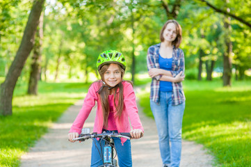 mother and daughter ride bikes in the forest