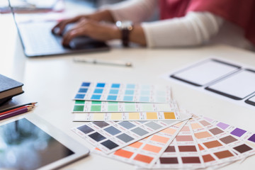 Young designers teamwork working with color samples for selection on office desk, Architects...