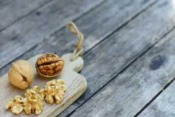Walnut nut in wooden bowl on wood table with green leaf background, copy space