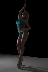 girl dancing on a pylon in a swimsuit. Black background