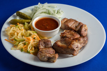 Tasty grilled meat, shish kebab on a blue background