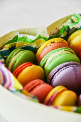colorful macaroons in a gift box with a bright paper on a light background