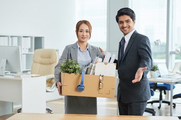 Portrait of happy businessman showing new workplace to young businesswoman at modern office