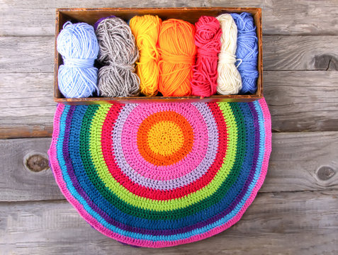 Knitted mat and colorful skeins of wollen yarn