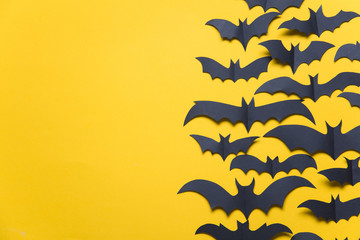 Halloween paper vampire bat decorations on an orange background.