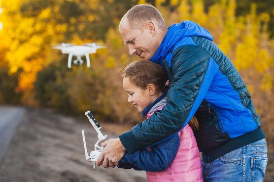 father and daughter with flying drone in the autumn park.