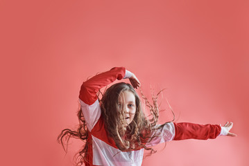 Young beautiful cute girl dancing on red background, modern slim hip-hop style teenage girl jumping © standret