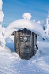 Old wooden hut in winter snowy forest in Finland, Lapland.