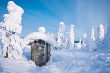 Old wooden hut in winter snowy forest in Finland, Lapland.