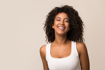 Portrait of laughing young woman against light background